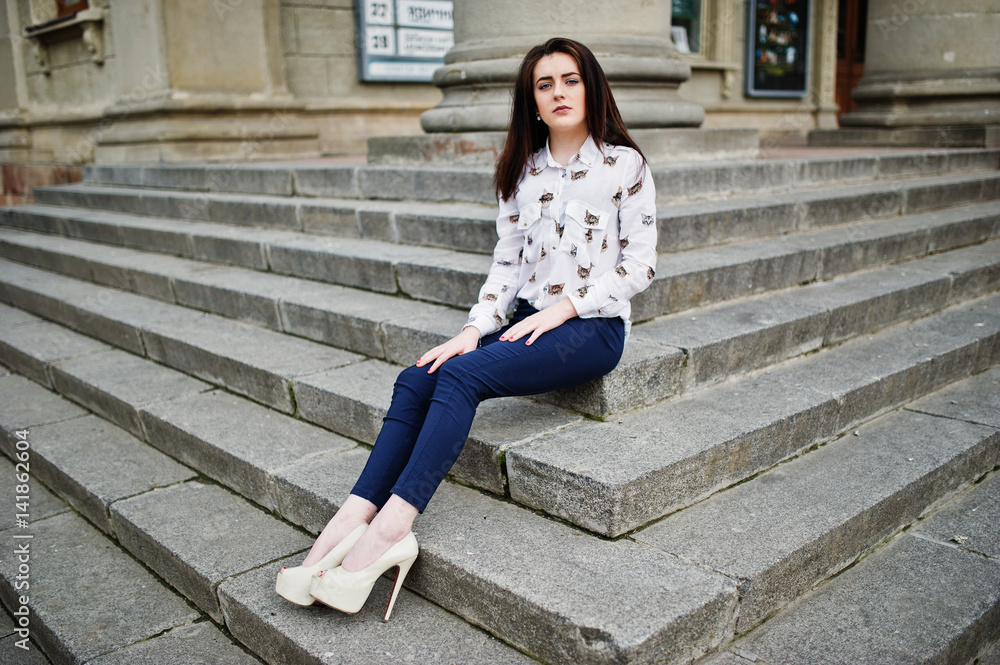 Young stylish brunette girl on shirt, pants and high heels shoes, posed at  stone stairs. Street fashion model concept. Stock Photo