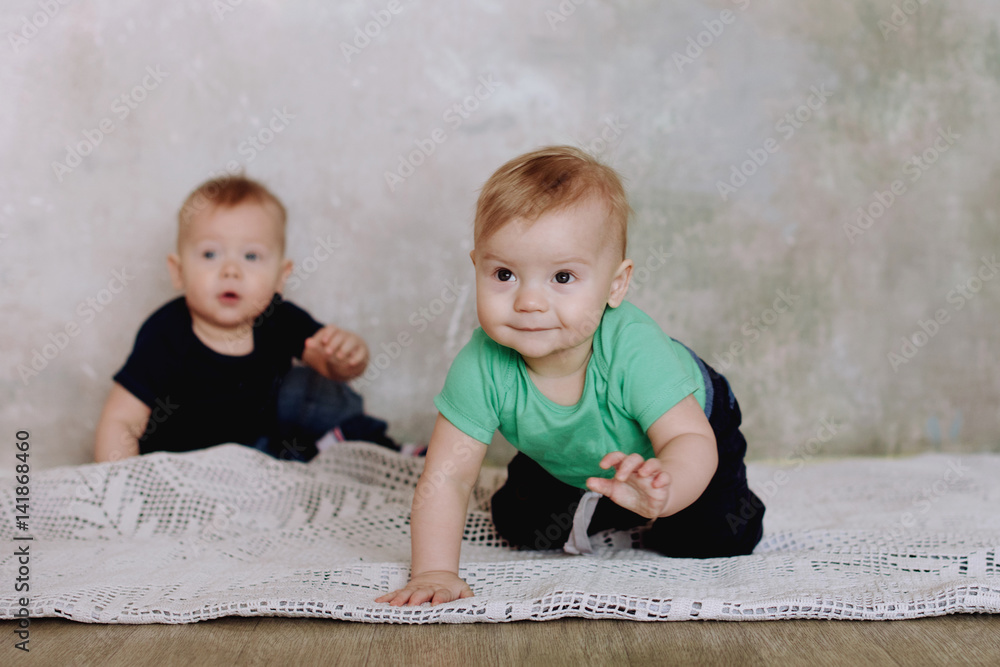 Fototapeta premium Two brother twins sitting. Two little kid boys watching at camera. Twins sitting together. People, children, friends and friendship concept
