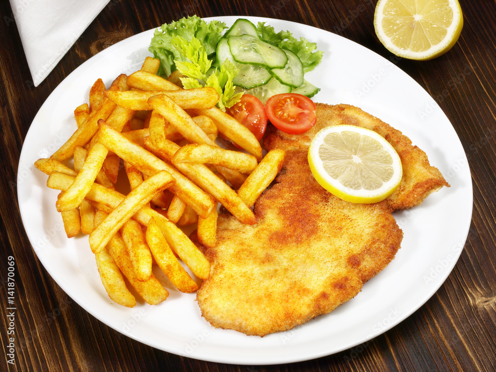 Wiener Schnitzel mit Pommes Frites und Salat StockFoto Adobe Stock