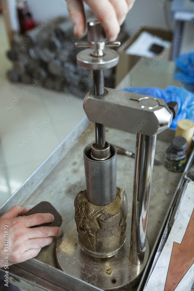 Civil engineer preparing a soil sample for a laboratory test in order to determine shear strength. Soil being tested for mechanical characteristics before construction works.