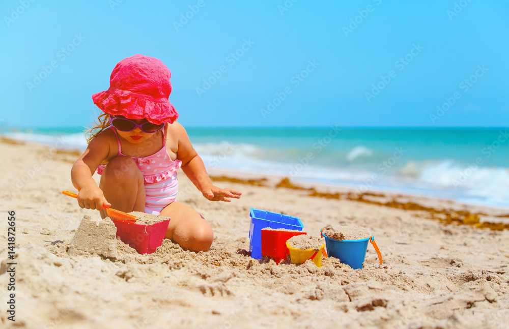 cute little girl play with sand on beach