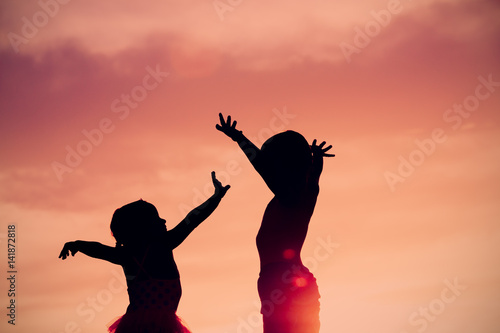 little boy and girl silhouettes play at sunset sky