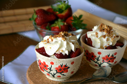 Refreshing snack chopped strawberries and whipped cream on a nice bowl.