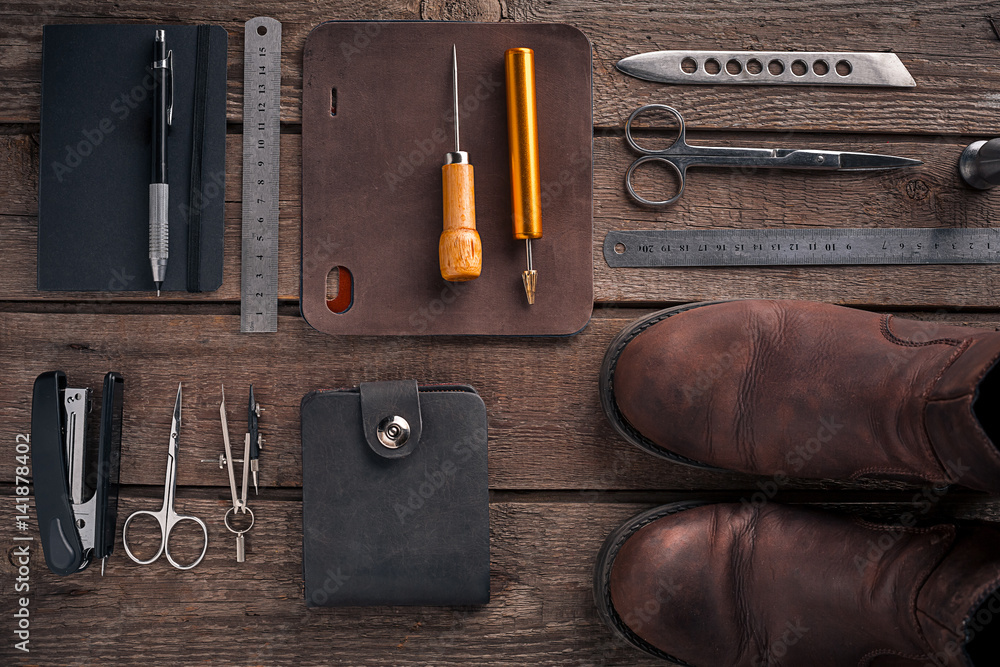Leather craft or leather working. Leather working tools and cut out pieces of leather on work desk . Leather craft or leather working. Leather working tools and cut out pieces of leather on work desk .