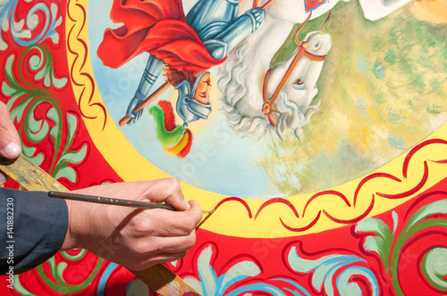 Hand of a sicilian cart painter while finishing some colored details.  Workshop of the sicilian folkloric craftsmanship Rosso Cinabro, Ragusa Ibla