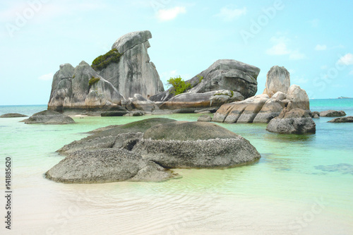Natural rock formation in the sea and on a white sand beach in Belitung Island in the afternoon, Indonesia. photo