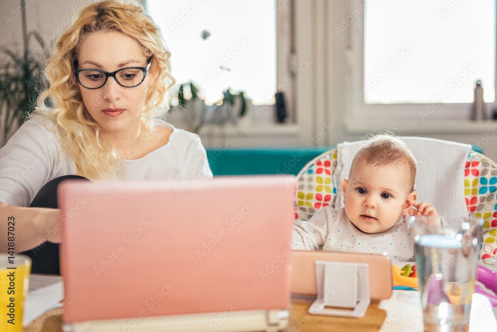 Mother with baby using laptop at home office Mother with baby using laptop at home office