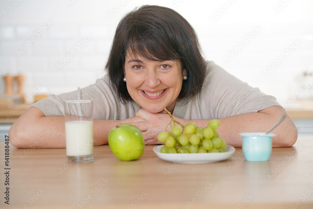 Cheerful woman in kitchen eating healthy food Cheerful woman in kitchen eating healthy food