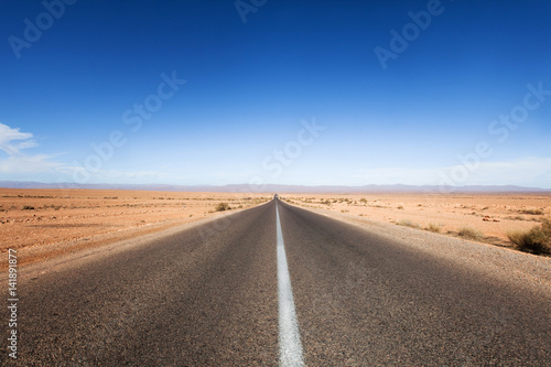 route droite au milieu d'un désert de sable 