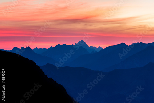 Spectacular blue mountain ranges silhouettes and pink violet clouds