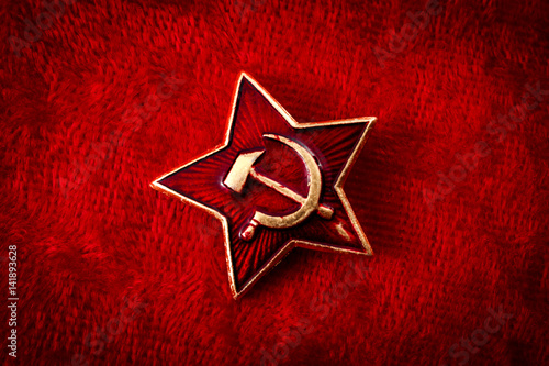 Obraz na płótnie Old Soviet badge with the red star, a sickle and a hammer reminiscent of the cold war era worn by the soldiers of the red army on their hats, isolated on red velvet with a grungy aesthetic w salonie
