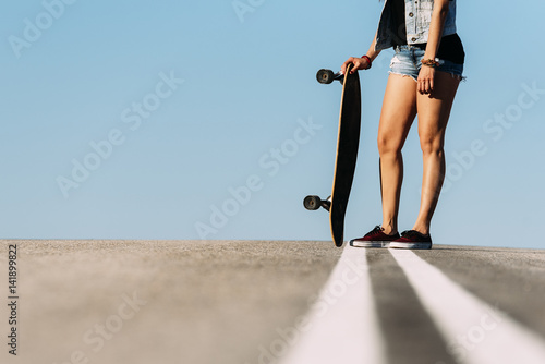 Beautiful skater woman posing with her longboard. photo