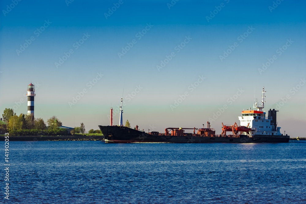 Black cargo oil tanker entering the port of Riga at sunny day