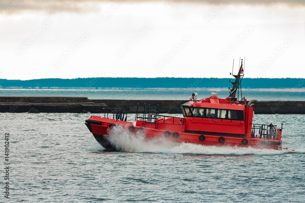 Fototapeta premium Red pilot ship sailing to Baltic sea past the breakwater dam