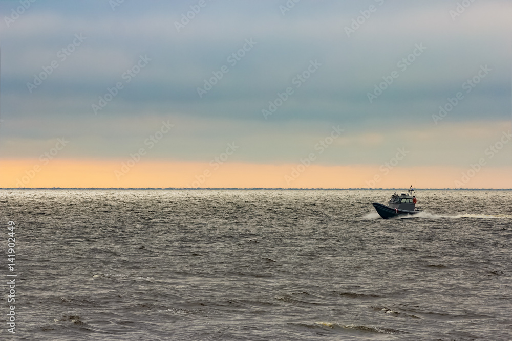 Small grey borger guard boat moving fast in still evening Small grey borger guard boat moving fast in still evening