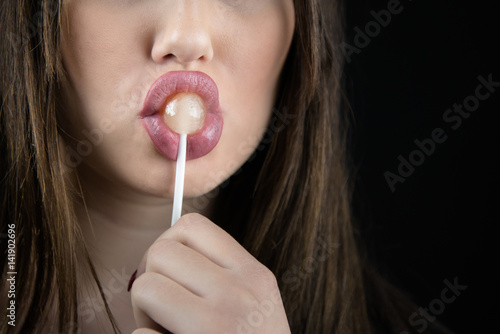Quadro em tela Juicy big lips of a young woman suck a lollipop, nice long fingers with red nail