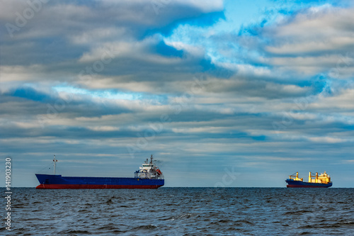 Blue cargo ships moored in still Baltic sea water