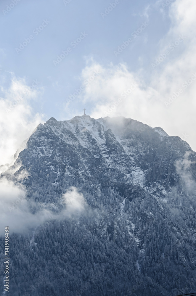 Carpathians Mountains, Bucegi  range with Cross in top of Caraiman Peak, pine forest with fog, winter time with snow