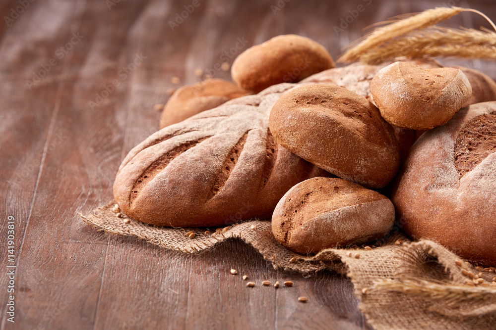 handmade tasty bread lying on burlap on the wooden table with flour, wheat and ears of wheat handmade tasty bread lying on burlap on the wooden table with flour, wheat and ears of wheat