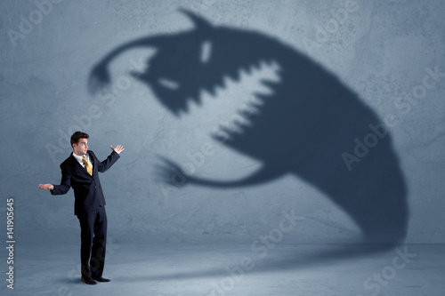 Business man afraid of his own shadow monster concept