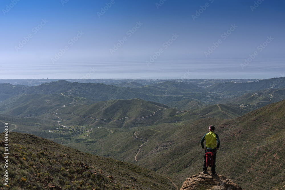 Obraz premium Hombre en la cima de la montaña que mira el paisaje montañoso
