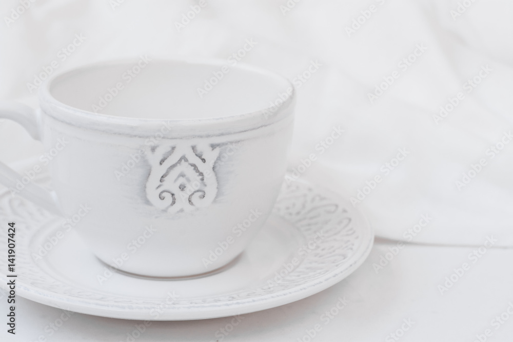 White relief ceramic tea cup with saucer on wood table cotton fabric, purity concept, minimalist, styled image for social media White relief ceramic tea cup with saucer on wood table cotton fabric, purity concept, minimalist, styled image for social media