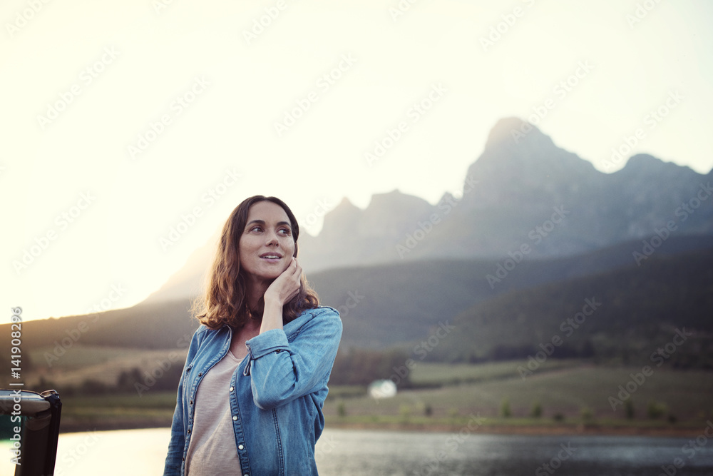 Woman looking away while standing at lakeshore against clear sky during sunset Woman looking away while standing at lakeshore against clear sky during sunset