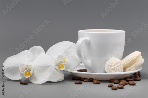 Orchid and white cup of coffee on a gray background photo