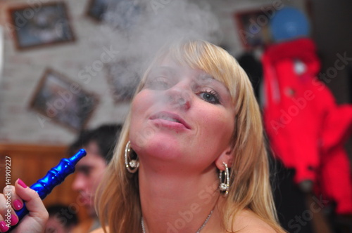 Beautiful blond girl with tea smoke hookah with pepper and mint photo