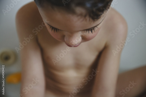 Close-up of naked boy sitting in bathtub photo