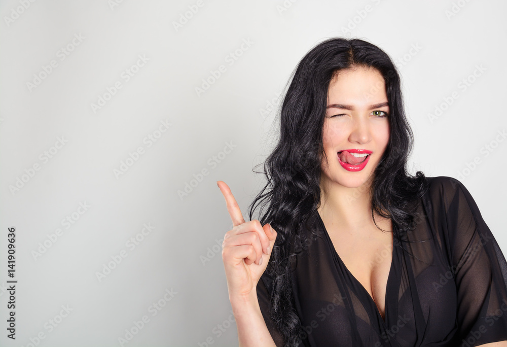 Beautiful brunette woman laughs and points with an index finger. Sale, share, gift, attention. Mock up. Beautiful brunette woman laughs and points with an index finger. Sale, share, gift, attention. Mock up.