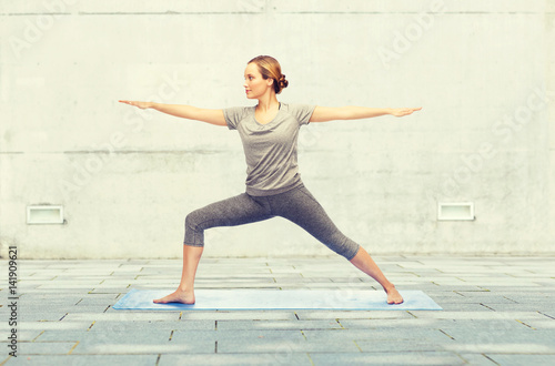 woman making yoga warrior pose on mat
