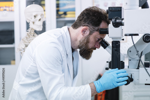 Scientist in laboratory looking through microscope