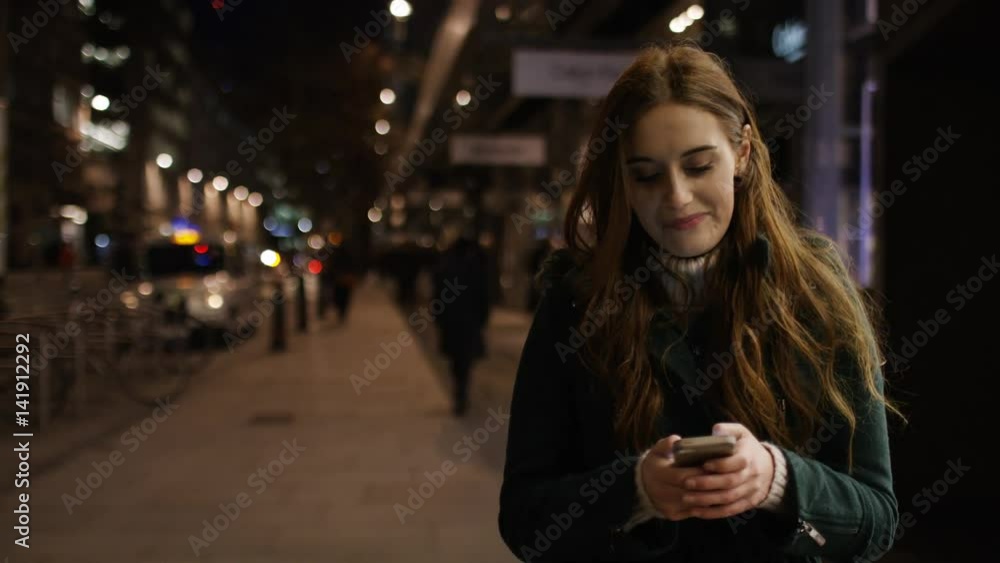 4K Attractive young woman walking through the city at night on her phone, in slow motion 4K Attractive young woman walking through the city at night on her phone, in slow motion