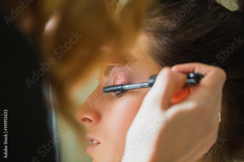 Makeup artist applying mascara on eyelash of girl