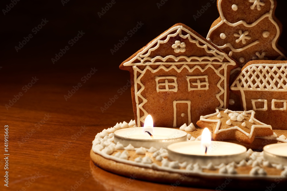 Homemade gingerbread house lit by candles on a dark background. Christmas dessert Homemade gingerbread house lit by candles on a dark background. Christmas dessert