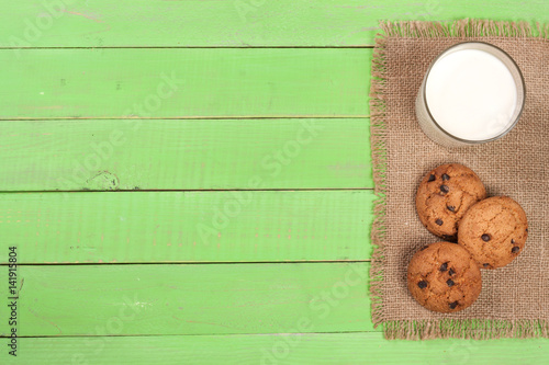 glass of milk with oatmeal cookies on a green wooden background with copy space for your text. Top view