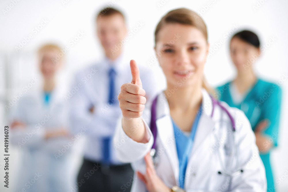 Attractive female doctor in front of medical group showing ok Attractive female doctor in front of medical group showing ok