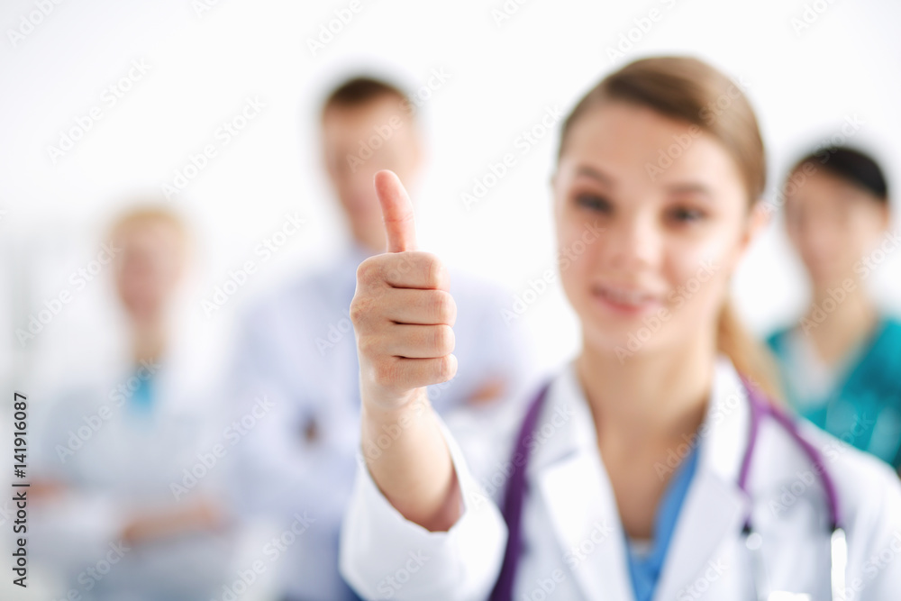 Attractive female doctor in front of medical group showing ok Attractive female doctor in front of medical group showing ok