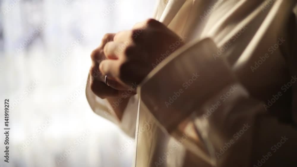 Groom buttoning up his white shirt before wedding ceremony. Close up. Soft light Groom buttoning up his white shirt before wedding ceremony. Close up. Soft light
