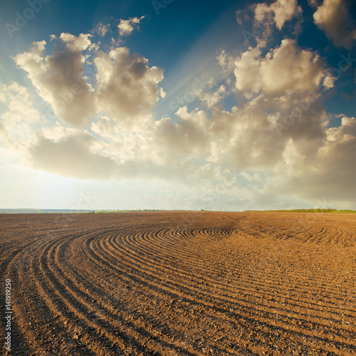 sunset in clouds over plowed field photo