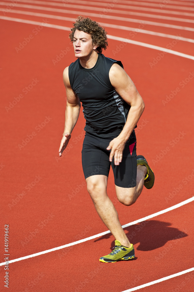 Muscular Male Athlete sprinting around track