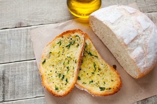 Fried bread with olive oil, garlic and herbs on a wooden table. Rustic style photo