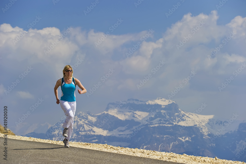 A women running along a mountain road.