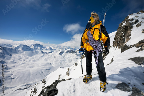 Fényképezés A mountaineer stating in her crampons with ice axes and ropes pauses to look at the incredible view