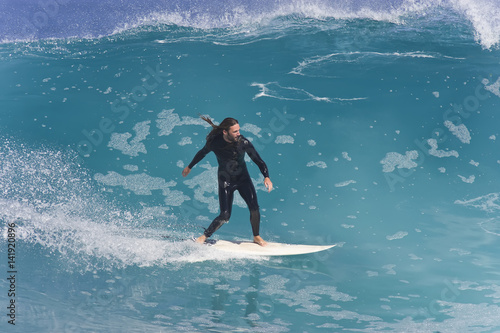 A Surfer carves along a big blue wave.