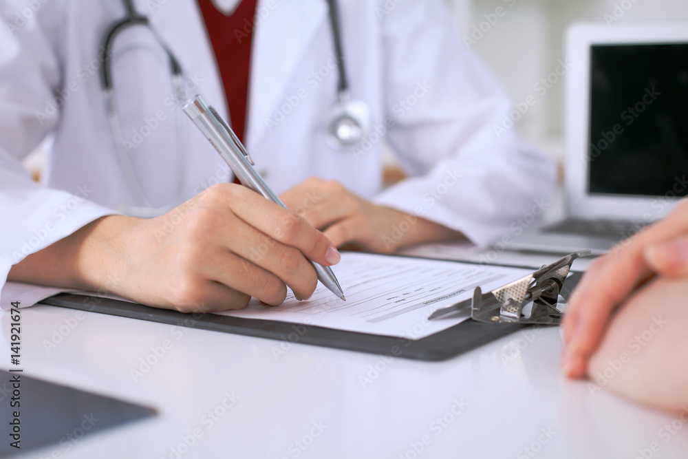 Close up of a female doctor filling up an application form while consulting patient. Medicine and health care concept Close up of a female doctor filling up an application form while consulting patient. Medicine and health care concept