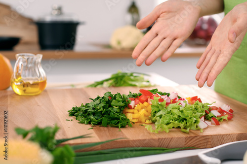 Close up of woman's hands cooking in the kitchen. Housewife offering ​​fresh salad. Vegetarian and healthily cooking concept