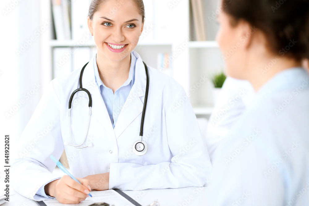 Friendly smiling doctor and patient sitting at the table. Very good news and high level medical service concept. Friendly smiling doctor and patient sitting at the table. Very good news and high level medical service concept.