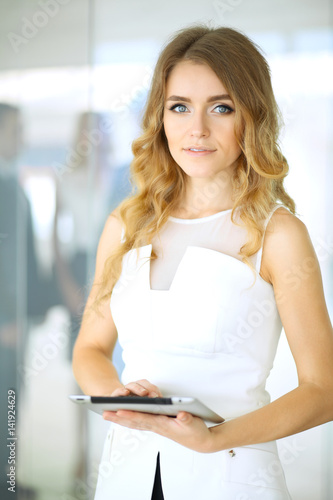 Free Download Blonde woman with touchpad computer looking at camera and smiling while business people are shaking hands over office background - GFXLoad